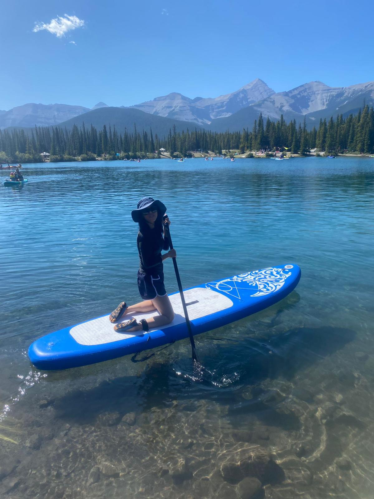 A chinese women kneeling on a paddleboard in the middle of a lake